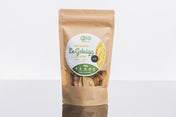 Eine braune Papiertüte mit der Aufschrift „LeGebäck – Zitrone 100 g“ und einem grün-weiß-gelben Etikett enthält vegane Bio-Zitronenkekse von Qio Food, präsentiert auf einem Regal.